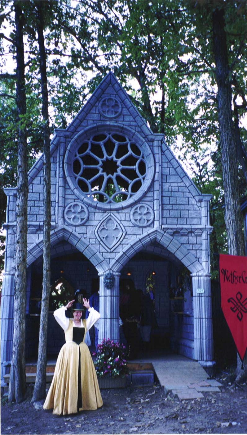 A lady in a yellow Cavalier-era dress stands in front of the booth.