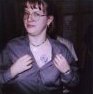 Kendra pulls open her sirt to reveal a large, blue daisy painted just below her collarbone.